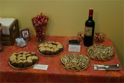 Dessert table with wine bottle, vase of chocolates and 4 plates of two kinds of cookies