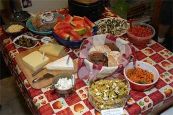 Picture of the food presentation -- humus, pita, watermelon, cheese board, bread basket, couscous salad, bruschetta and mushrooms