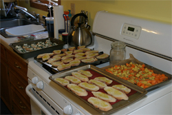 Trays of baguette slices and potatos waiting to go in the oven