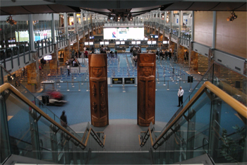 View down staircase to two large wooden totem poles in large airport corridor